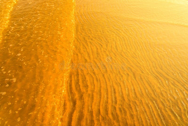 Luz de oro que refleja de una onda de agua en el mar y de la arena en puesta del sol imagenes de archivo Luz de oro que refleja de una onda de agua en el mar y de la arena en puesta del sol imagenes de archivo