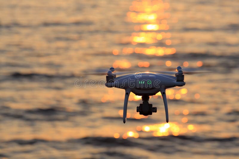 KAGAWA, JAPAN - JUNE 8, 2017: Remote controlled drone Dji Phantom4Pro equipped with high resolution video camera flying in air and sparkle sunlight on sea. KAGAWA, JAPAN - JUNE 8, 2017: Remote controlled drone Dji Phantom4Pro equipped with high resolution video camera flying in air and sparkle sunlight on sea.