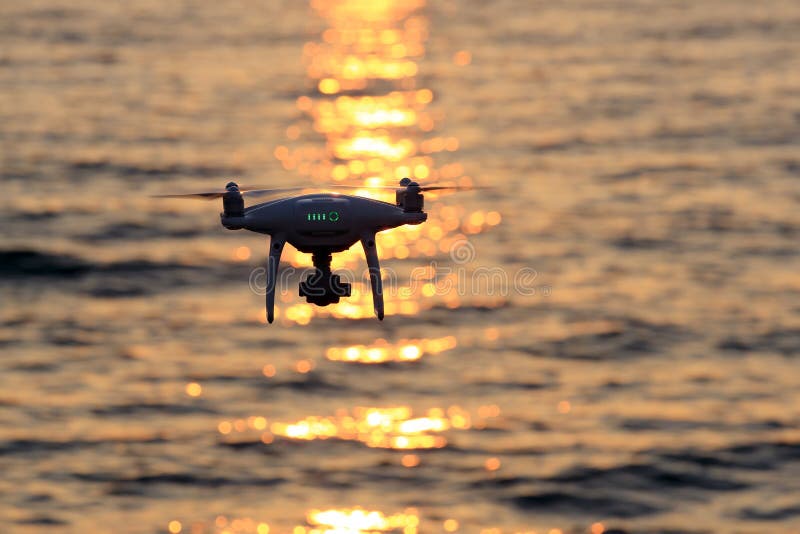 KAGAWA, JAPAN - JUNE 8, 2017: Remote controlled drone Dji Phantom4Pro equipped with high resolution video camera flying in air and sparkle sunlight on sea. KAGAWA, JAPAN - JUNE 8, 2017: Remote controlled drone Dji Phantom4Pro equipped with high resolution video camera flying in air and sparkle sunlight on sea.