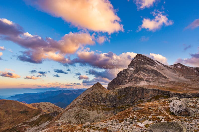 Luz del sol caliente pasada en el valle alpino con los picos de montaña que brillan intensamente y las nubes escénicas Montañas f fotografía de archivo libre de regalías Luz del sol caliente pasada en el valle alpino con los picos de montaña que brillan intensamente y las nubes escénicas Montañas f fotografía de archivo libre de regalías