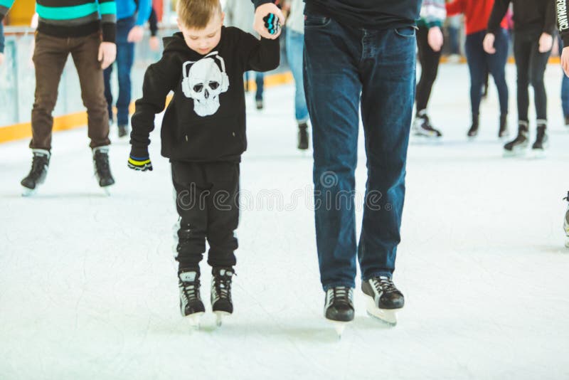 LVIV, UKRAINE - February 3, 2019: father teaching son how to skate on ski rink