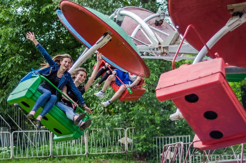 LVIV, UKRAINE - JUIN 2016 : Deux beaux ados de jeunes filles montent sur le carrousel en parc d'attractions, avec des émotions jo photographie stock libre de droits LVIV, UKRAINE - JUIN 2016 : Deux beaux ados de jeunes filles montent sur le carrousel en parc d'attractions, avec des émotions jo photographie stock libre de droits