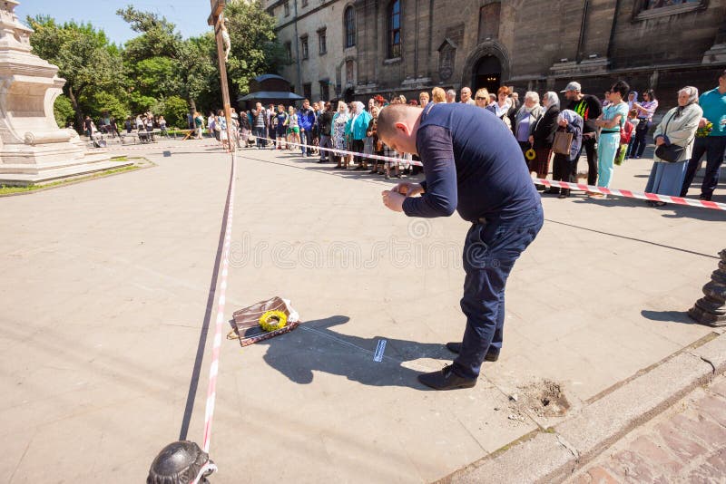 LVIV, UKRAINE - JUNE 18: A policeman collects evidence as the body of a pedestrian lays next to an overturned SUV on 18 June 2017 in Lviv, Ukraine. LVIV, UKRAINE - JUNE 18: A policeman collects evidence as the body of a pedestrian lays next to an overturned SUV on 18 June 2017 in Lviv, Ukraine.