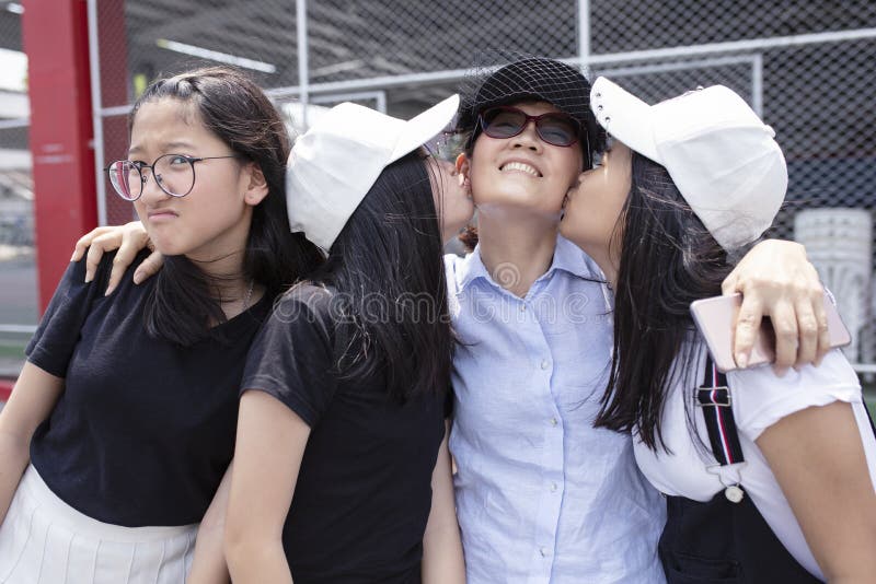 Lyckasinnesrörelse av asiatisk teenger som kysser på lyckaframsida av kvinnan arkivfoto Lyckasinnesrörelse av asiatisk teenger som kysser på lyckaframsida av kvinnan arkivfoto