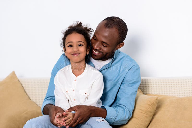 Lycklig afrikansk amerikanfader och dotter på soffan hemma
