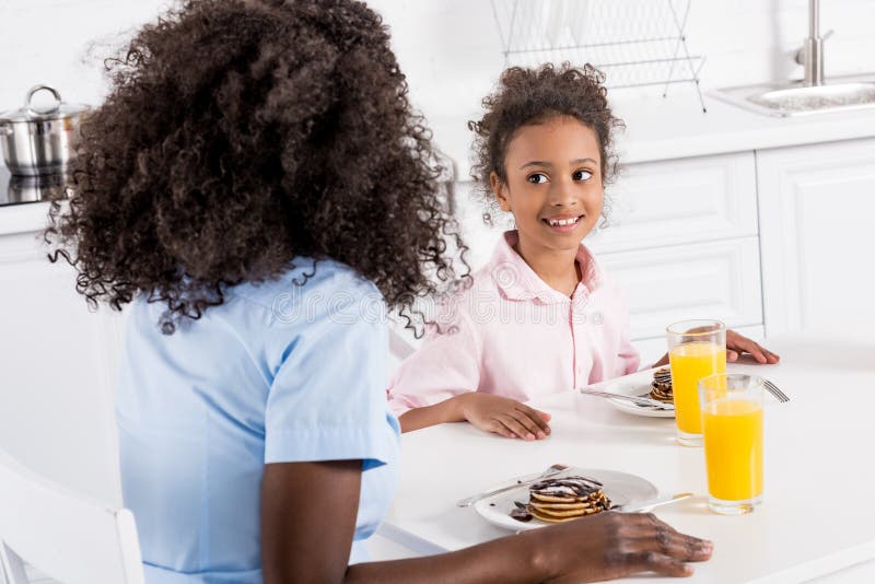 lycklig afrikansk amerikanfamilj som har pannkakor och orange fruktsaft för frukost arkivfoto lycklig afrikansk amerikanfamilj som har pannkakor och orange fruktsaft för frukost arkivfoto