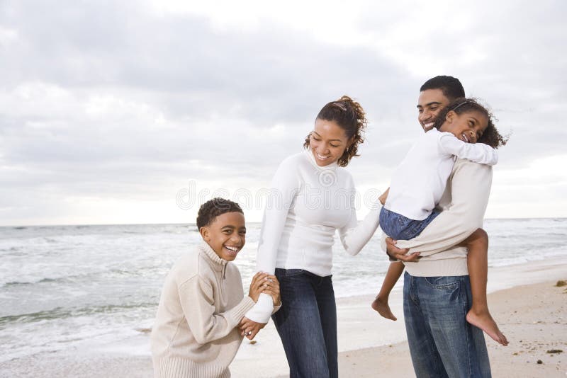 Lycklig afrikansk amerikanstrandfamilj fyra arkivfoto