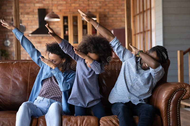 Lycklig afrikansk familj sitter på soffan och visar en db-gest royaltyfri bild