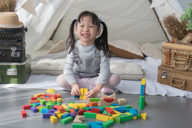 Lycklig asiatisk flicka som spelar med färgrika kvarter royaltyfri foto