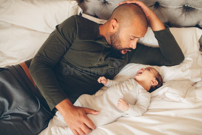 Lycklig fader med hans son som spelar på sängen royaltyfri fotografi Lycklig fader med hans son som spelar på sängen royaltyfri fotografi