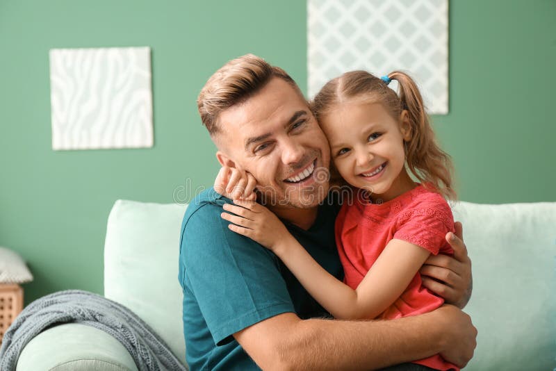 Lycklig fader och dotter som hemma kramar arkivbild Lycklig fader och dotter som hemma kramar arkivbild