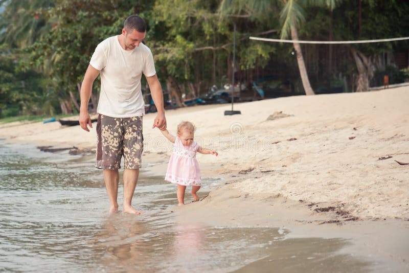 Lycklig fader och liten dotter som går samman med innehavhänder på stranden arkivbilder Lycklig fader och liten dotter som går samman med innehavhänder på stranden arkivbilder