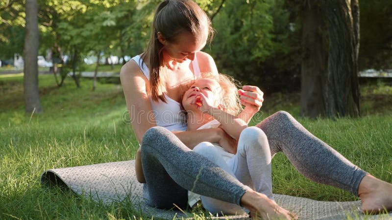 Lycklig familj av den unga sportiga modern och lilla gulliga dottern som har roligt utomhus