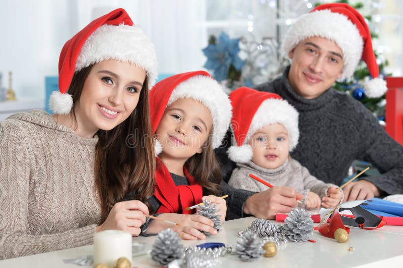 Lycklig familj i jultomtenhattar som förbereder sig för jul arkivbild Lycklig familj i jultomtenhattar som förbereder sig för jul arkivbild