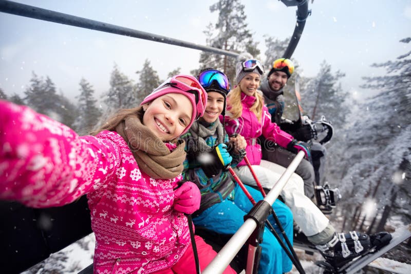 Lycklig familj i klättring för kabelbil som skidar terräng