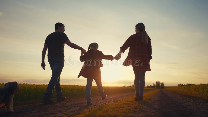 Lycklig familj i parken vid sunset. Folk grupperar far och döttrar som går i naturen vid solnedgången i parken. vänlig