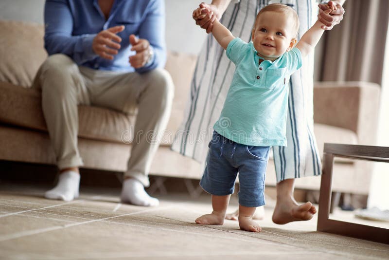 Lycklig familj - le behandla som ett barn pojken som gör första steg royaltyfri fotografi Lycklig familj - le behandla som ett barn pojken som gör första steg royaltyfri fotografi