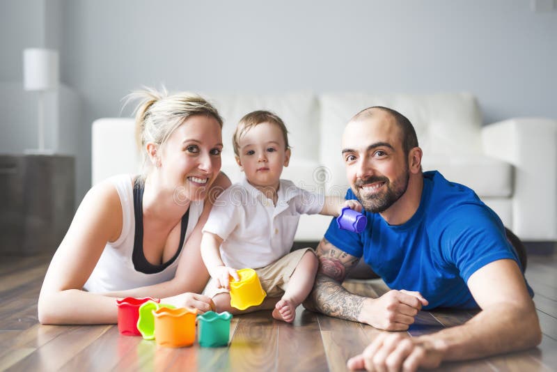 Lycklig familj med föräldrar och sonen som spelar med färgrika kvarter i livingroomen royaltyfria bilder Lycklig familj med föräldrar och sonen som spelar med färgrika kvarter i livingroomen royaltyfria bilder