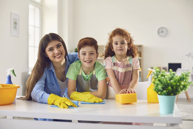 Portrait of happy family with mom and two children cleaning up at home. Cheerful parent and kids doing domestic chores together indoors. Portrait of happy family with mom and two children cleaning up at home. Cheerful parent and kids doing domestic chores together indoors
