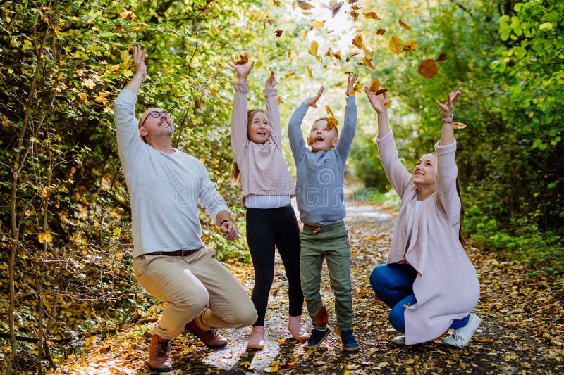 Lycklig familj som har kul med en löv i höstskogen. royaltyfri bild