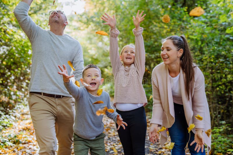 Lycklig familj som har kul med en löv i höstskogen. royaltyfri fotografi