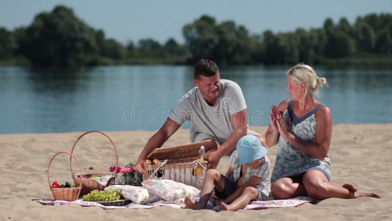 Lycklig familj som har picknicken på stranden