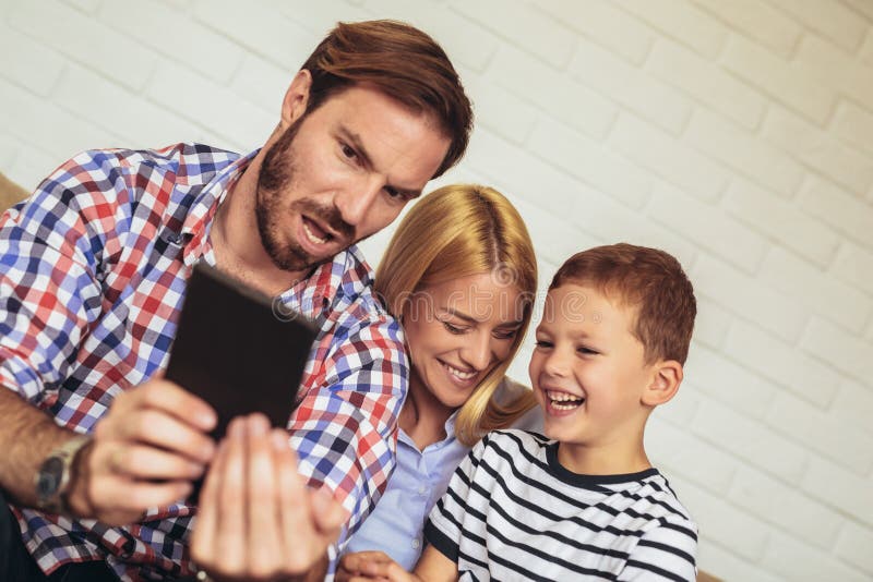 Lycklig familj som hemma använder den digitala minnestavlan arkivfoton Lycklig familj som hemma använder den digitala minnestavlan arkivfoton