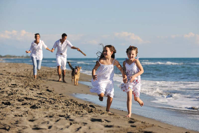 Lycklig familj som leker med hunden på strand royaltyfri foto Lycklig familj som leker med hunden på strand royaltyfri foto