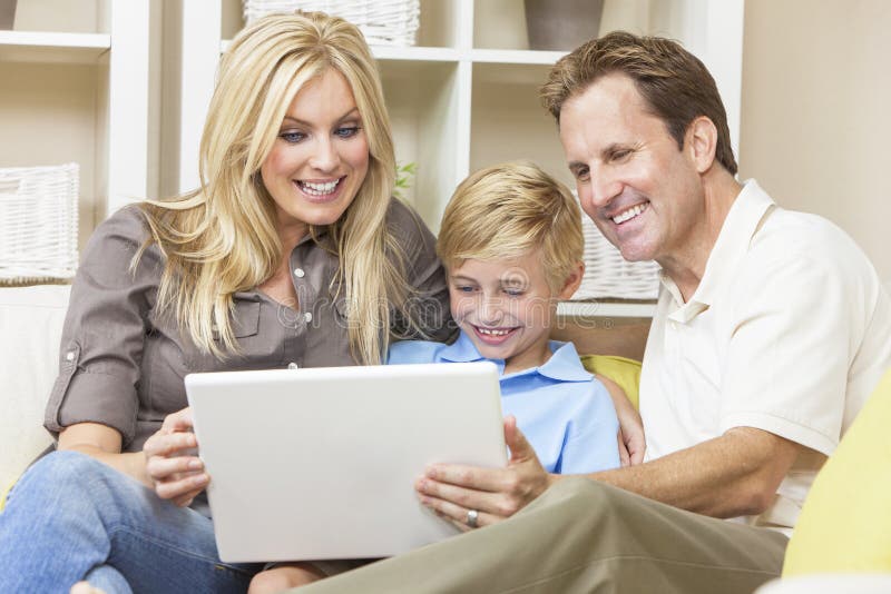 Lycklig familj som sitter på sofaen genom att använda bärbar datordatoren arkivbild Lycklig familj som sitter på sofaen genom att använda bärbar datordatoren arkivbild
