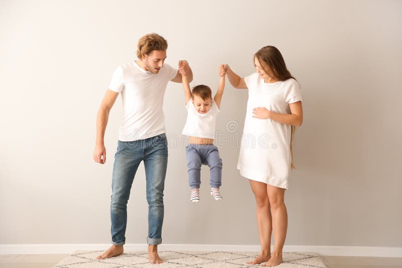 Lycklig familj som spelar nära den vita väggen arkivbild Lycklig familj som spelar nära den vita väggen arkivbild