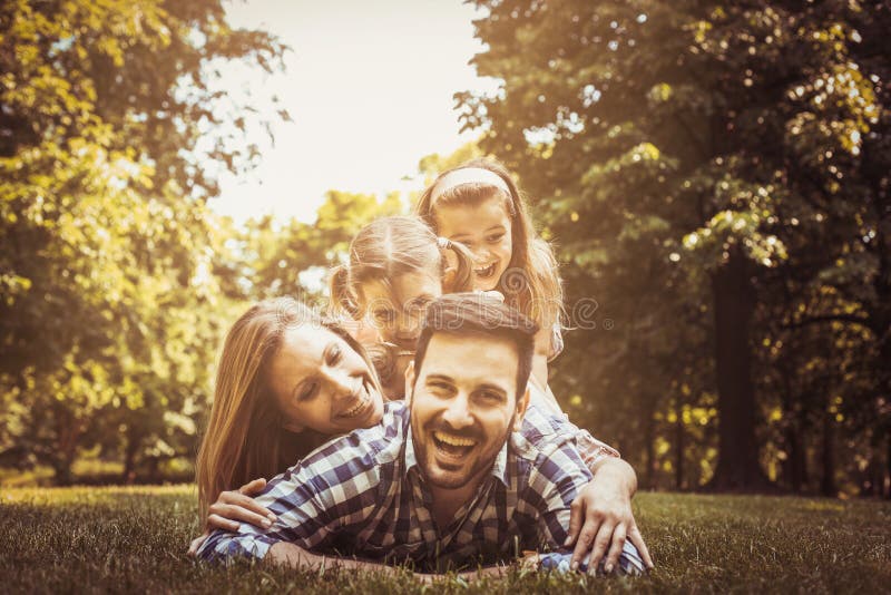Lycklig familj som tillsammans tycker om i sommardag Ligga för små flickor royaltyfri fotografi Lycklig familj som tillsammans tycker om i sommardag Ligga för små flickor royaltyfri fotografi