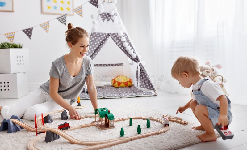 Lycklig familjmoder och barnson som spelar i leksakjärnväg i pl