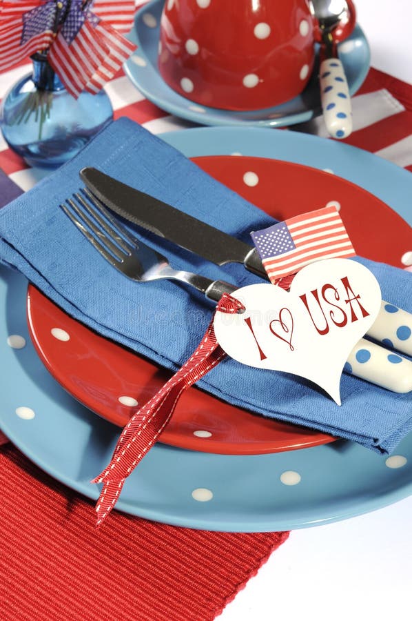 Happy Fourth of July dining table place setting in red, white and blue color theme with USA Stars and Stripes flag and heart gift tag with sample text. Happy Fourth of July dining table place setting in red, white and blue color theme with USA Stars and Stripes flag and heart gift tag with sample text.