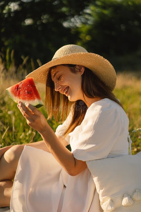Lycklig flicka i utomhusparken med fräschande vattenmelonfrukt. kvinna äter en bit vattenmelon. Sommarflicka i utomhusfältet med frisk uppfriskande vattenmelonfrukt. sommarpicknicker. Vattentäthet, bläckfiskfilt.