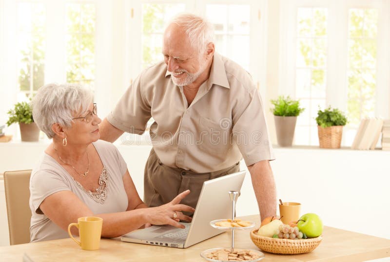 Lycklig home pensionär för datorpar arkivfoto