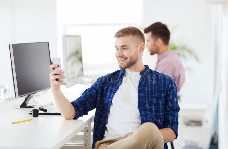 Lycklig idérik man som smsar på mobiltelefonen på kontoret arkivfoton Lycklig idérik man som smsar på mobiltelefonen på kontoret arkivfoton