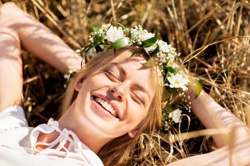 Lycklig kvinna i krans av blommor som ligger på sugrör arkivfoton Lycklig kvinna i krans av blommor som ligger på sugrör arkivfoton