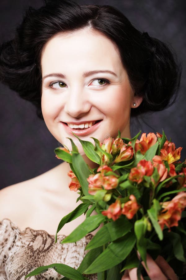 Lycklig kvinna med blommor i händer Den unga attraktiva unga flickan rymmer buketten av röda och gula blommor arkivbild Lycklig kvinna med blommor i händer Den unga attraktiva unga flickan rymmer buketten av röda och gula blommor arkivbild