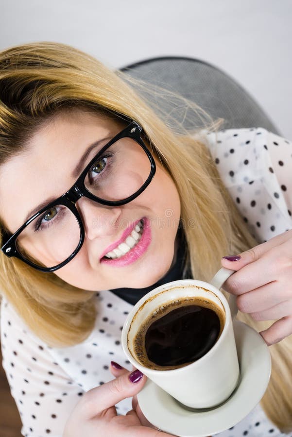 Lycklig kvinna p? kontoret som dricker varmt kaffe arkivbilder Lycklig kvinna p? kontoret som dricker varmt kaffe arkivbilder