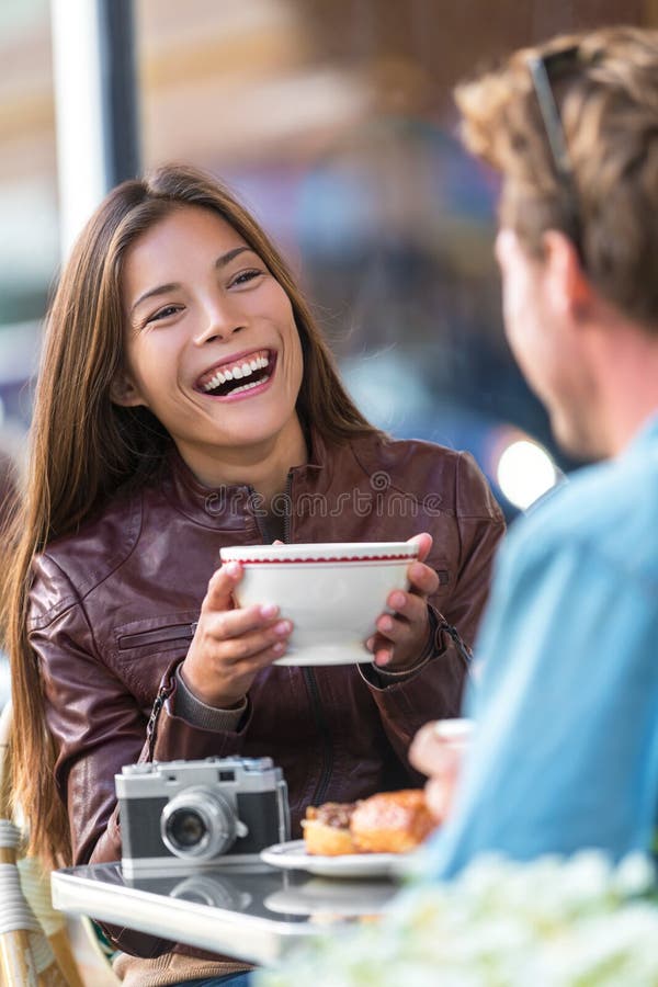 Lycklig kvinna som dricker kaffe på kafét Asiatisk flicka, konversation med manvännen som skrattar sammanträde på restaurangtabel