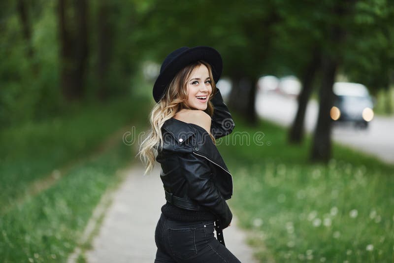 Lycklig le flicka i svartläderomslag och i moderiktig svart hatt arkivfoto Lycklig le flicka i svartläderomslag och i moderiktig svart hatt arkivfoto