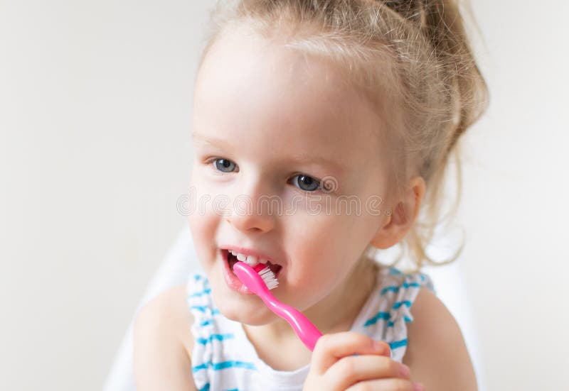 Lycklig liten flicka som borstar hennes tänder, rosa tandborste, tand- hygien, morgon royaltyfria foton Lycklig liten flicka som borstar hennes tänder, rosa tandborste, tand- hygien, morgon royaltyfria foton