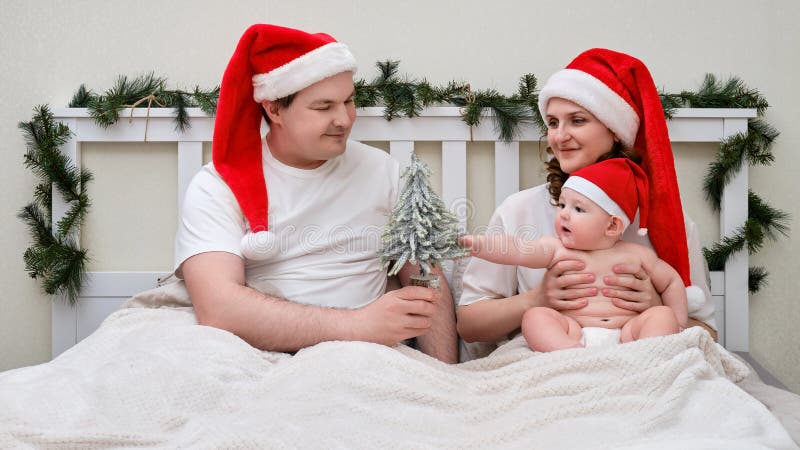 Lycklig man och hustru med barn i sängen som dekorerats för julklappar och royaltyfri foto