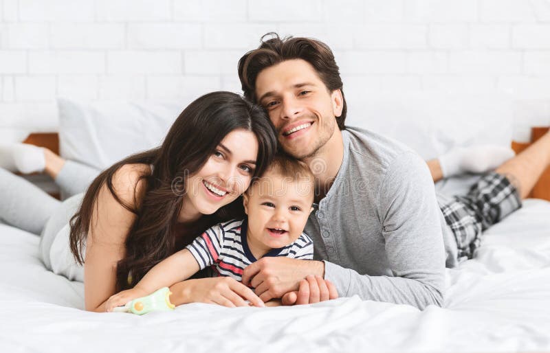 Lycklig millennial familjbindning på säng med behandla som ett barn royaltyfria foton Lycklig millennial familjbindning på säng med behandla som ett barn royaltyfria foton