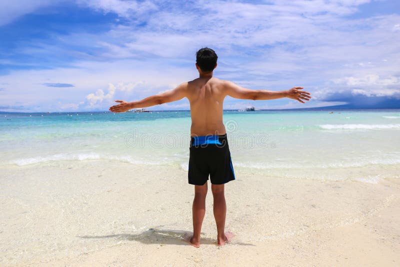 Lycklig och gladlynt shirtless man i baddräkten som lyfter händer upp på strandvattnet royaltyfri bild Lycklig och gladlynt shirtless man i baddräkten som lyfter händer upp på strandvattnet royaltyfri bild