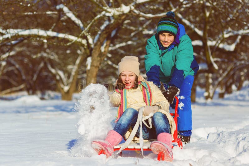 Lycklig pojke och flicka som sledding i den utomhus- vintern royaltyfri fotografi Lycklig pojke och flicka som sledding i den utomhus- vintern royaltyfri fotografi