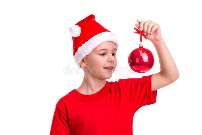 Lycklig pojke, santa hatt på hans huvud som rymmer och ser den röda julbollen Begrepp: jul eller lyckligt nytt år fotografering för bildbyråer Lycklig pojke, santa hatt på hans huvud som rymmer och ser den röda julbollen Begrepp: jul eller lyckligt nytt år fotografering för bildbyråer