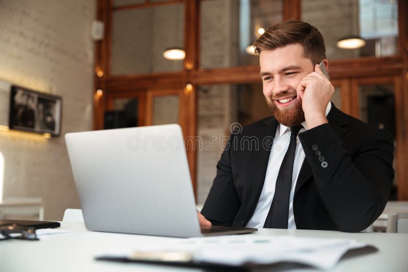 Lycklig ung affärsman i svart dräkt som talar på mobiltelefon, l royaltyfri bild Lycklig ung affärsman i svart dräkt som talar på mobiltelefon, l royaltyfri bild