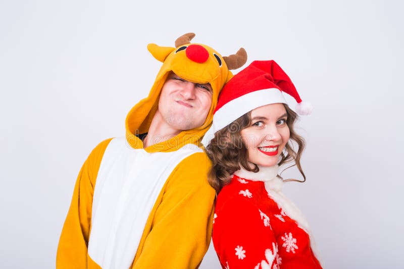 Lycklig ung kvinna i den Santa Claus hatten och mannen i karnevaldräkt av hjortar Gyckel-, ferie-, skämt- och julbegrepp royaltyfri foto Lycklig ung kvinna i den Santa Claus hatten och mannen i karnevaldräkt av hjortar Gyckel-, ferie-, skämt- och julbegrepp royaltyfri foto