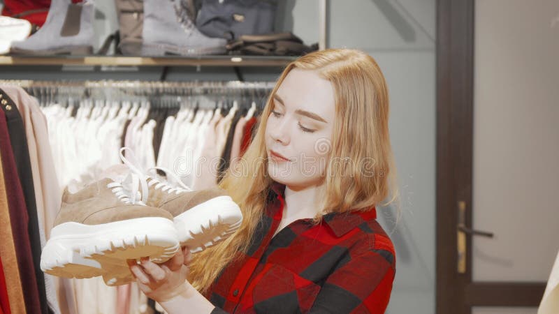 Lycklig ung kvinna som leker till kameran medan hon shoppar efter skor